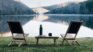 Wooden folding camp chairs and table by a lake