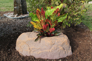 Planter Faux Rock 132 in Autumn Bluff in garden with flowers planted