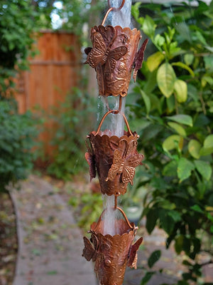 Butterfly Theme Copper Rain Chain with water flowing through multiple cups during rainstorm