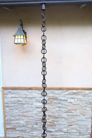 bronze Cast Zen Loops Rain Chain full length image next to home