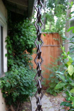 Rain water flowing down bronze Diamond Links Rain Chain on home