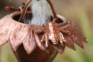 Closeup of Sunflower Copper Rain Chain with bee accent and water flowing through cup