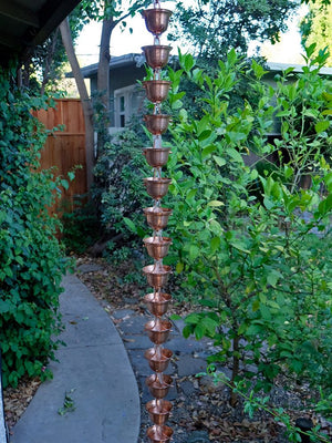 Copper Bell Cups Rain Chain on house with water flowing through multiple cups