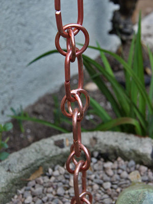 Link & Loop Copper Rain Chain running into a flower pot with stones