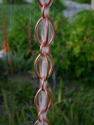 Full length image of Oval Loop Copper Rain Chain with water running through it