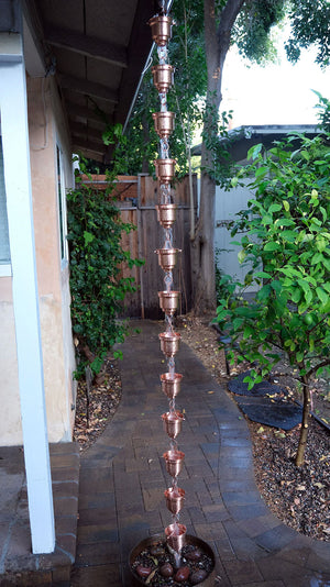 Copper Naoki Cups Rain Chain on house with water flowing through multiple cups
