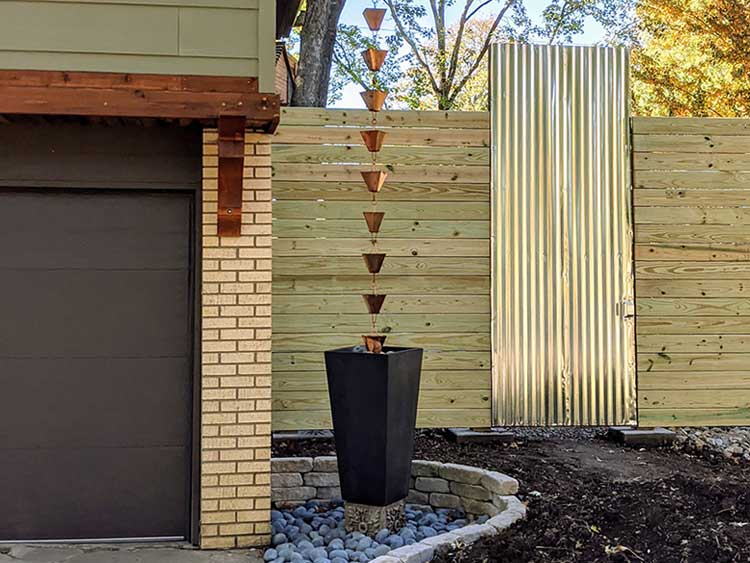 Extra Large Square Cups Rain Chain in Copper anchored by a planter with rocks