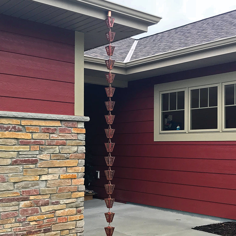 Arts & Crafts Rain Chain hanging at the corner of an entryway on a red house with stone. 