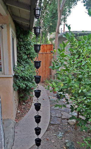Black Naoki Cups Rain Chain on house with water flowing through multiple cups