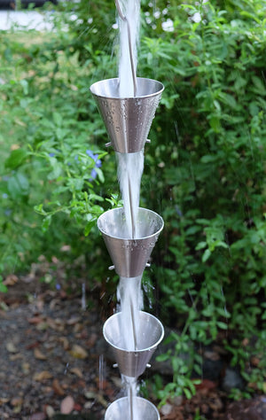 Full length image of stainless colored Steel Cups Rain Chain with water running through cups