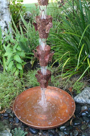Hand Hammered Copper Dish with Loop securing rain chain to the ground with water running through rain chain