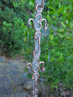 Closeup of OM Cast Link Rain Chain in brass with water flowing through it