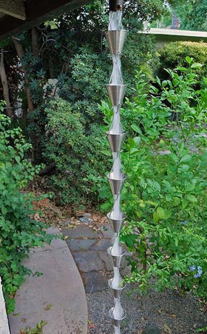 Full length image of stainless colored Steel Cups Rain Chain on home with water running through cups