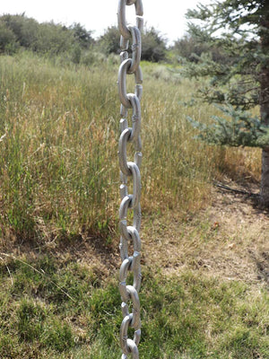 Full length view of XL Cast Oval Links Rain Chain in clear powder-coated aluminum