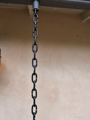 Cast oval links rain chain hanging from installation kit on a gutter