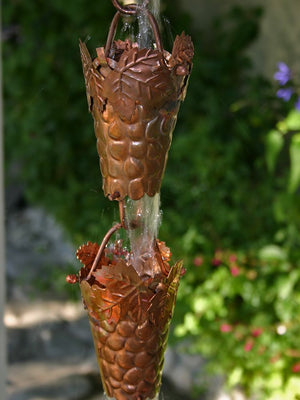 Grape Leaf Theme Copper Rain Chain with water flowing through multiple cups