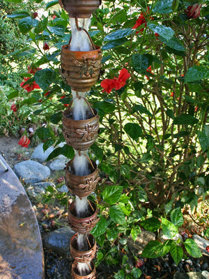 Honeybee & Hive Copper Rain Chain with bee accent in garden and water flowing through multiple cups