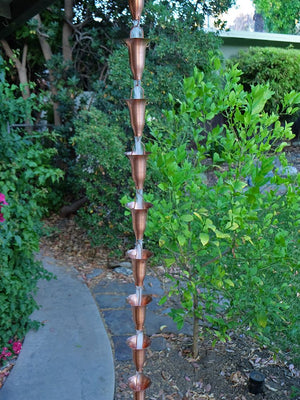 Copper Honeysuckle Rain Chain hanging from a gutter with water running through multiple cups