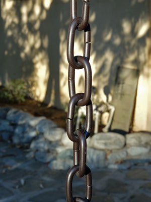 Large Link Rain Chain in bronze hanging from a home