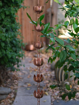 copper plated lily flower cups rain chain hanging in a garden