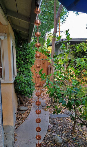 full length view of lily flower cups rain chain hanging from a home