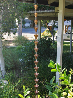 Star Flower Cups Rain Chain in platted copper on house with water flowing through multiple cups