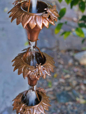 Sunflower Copper Rain Chain with bee accent and water flowing through multiple cups