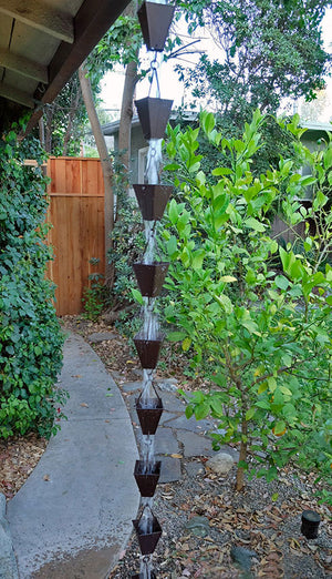 Bronze Tapered Square Cups Rain Chain on house with water flowing through multiple cups